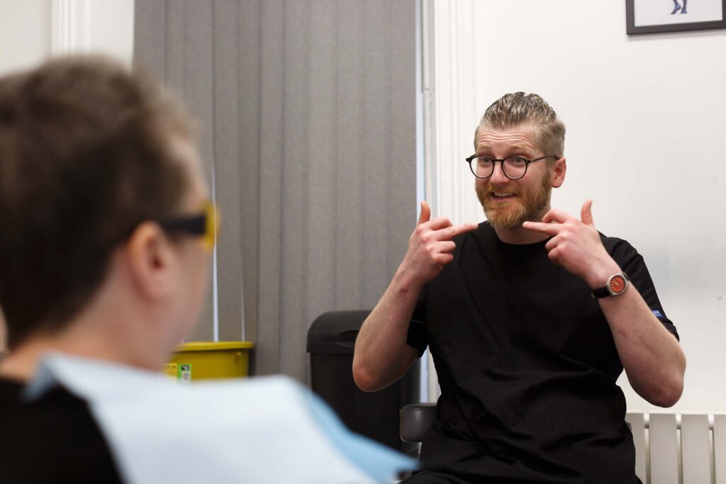 Dr. Tom Firar chatting to patient in treatment room, smiling, Skipton Road Dental, Colne