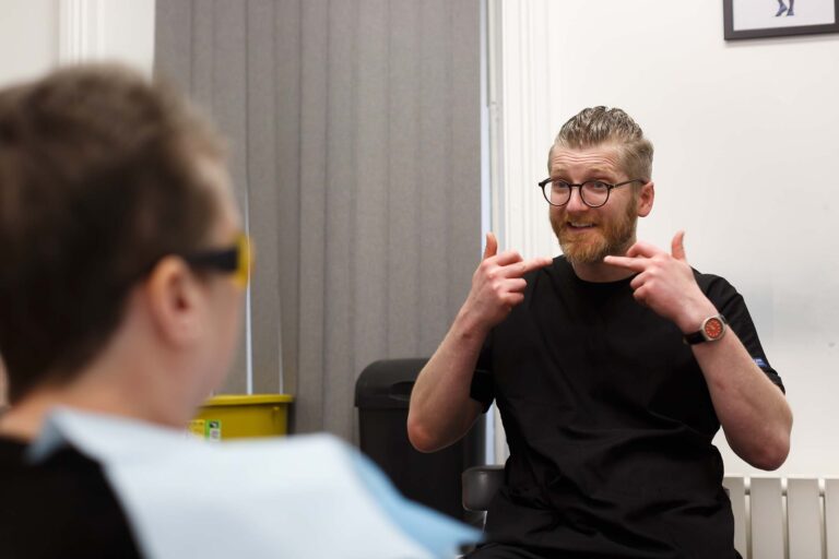 Dr. Tom Firar chatting to patient in treatment room, smiling, Skipton Road Dental, Colne